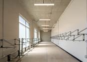 Thumbnail 5 of 36 - A long hallway with a series of stairs on the right side.