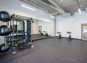 Thumbnail 20 of 36 - A gym with a variety of equipment including a squat rack, kettlebells, and a mirror.