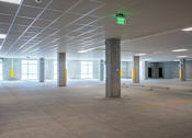 Thumbnail 6 of 36 - A large, empty parking garage with a green exit sign.