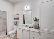 Thumbnail 12 of 23 - Modern bathroom with granite vanity and mirror at The Mill Old Town Apartments, Lewisville, 75057