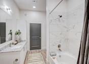 Thumbnail 18 of 23 - Modern bathroom with marble tile shower at The Mill Old Town Apartments, Lewisville