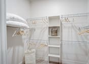 Thumbnail 11 of 19 - a closet with white curtains and white shelves and a bed with white pillows
