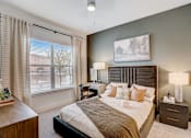 Thumbnail 9 of 23 - Bedroom with tufted headboard and window views at The Mill Old Town Apartments, Texas, 75057