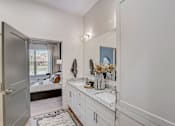 Thumbnail 8 of 19 - a bathroom with a sink and a mirror and a door to a bedroom