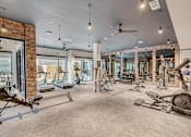 Thumbnail 5 of 23 - Fitness center with cardio and strength equipment at The Mill Old Town Apartments, Lewisville, 75057
