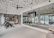 Thumbnail 6 of 23 - Fitness center with mirrored walls and cardio equipment at The Mill Old Town Apartments, Lewisville, Texas