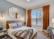 Thumbnail 11 of 23 - Bedroom with wooden bed frame and large mirror at The Mill Old Town Apartments, Lewisville, TX