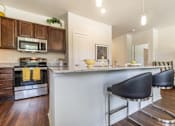 Thumbnail 5 of 16 - Kitchen with granite countertops and breakfast bar at Auberge of Tyler apartments in Tyler TX.
