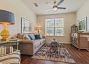 Thumbnail 4 of 16 - Bright living room with ceiling fan at Auberge of Tyler apartments in Tyler TX.
