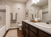 Thumbnail 13 of 24 - Modern apartment bathroom with a large vanity, bathtub, shower, and updated fixtures at Auberge of Tyler.
