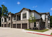 Thumbnail 2 of 24 - Apartment building with attached garages and landscaped grounds at Auberge of Tyler.