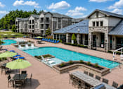 Thumbnail 24 of 24 - Resort-style swimming pool with lounge chairs surrounded by apartment buildings at Auberge of Tyler.