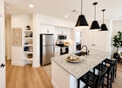 Thumbnail 16 of 47 - Modern apartment kitchen with oversized island, granite countertops and stainless appliances.