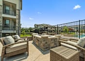 Thumbnail 3 of 16 - Outdoor patio with stone fireplace at Auberge of Tyler apartments in Tyler TX.