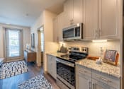 Thumbnail 23 of 35 - a kitchen with white cabinets and granite countertops at One Preston Station, Celina, 75009