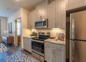 Thumbnail 16 of 35 - a kitchen with white cabinets and stainless steel appliances at One Preston Station, Texas
