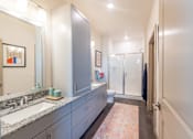 Thumbnail 27 of 35 - a bathroom with blue cabinets and a pink rug at One Preston Station, Celina