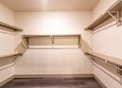 Thumbnail 22 of 35 - a walk in closet with white walls and a dark wood floor  at One Preston Station, Texas