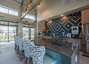 Thumbnail 9 of 35 - a kitchen with a long counter and a bunch of chairs in front of it at One Preston Station, Celina, 75009