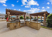 Thumbnail 18 of 19 - Outdoor grilling stations by the resort-style pool at Auberge of Burleson apartments in Burleson TX.