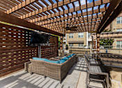 Thumbnail 16 of 19 - Outdoor lounge patio with seating and television at Auberge of Burleson apartments in Burleson TX.