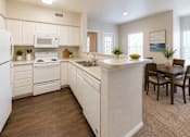 Thumbnail 25 of 37 - A kitchen with white appliances and wooden floors.
