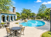 Thumbnail 2 of 37 - A pool with a table and chairs in front of a blue house.