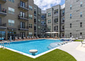 Thumbnail 13 of 19 - A swimming pool in front of apartment buildings.