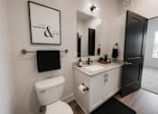 Thumbnail 22 of 23 - A bathroom with a toilet, sink, and a mirror.
