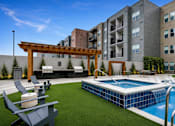 Thumbnail 3 of 23 - A pool with a slide and a pergola in the foreground with apartment buildings in the background.