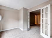 Thumbnail 8 of 15 - an empty living room with open doors to a hallway