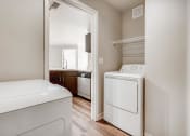 Thumbnail 5 of 29 - A washer and dryer in a laundry room with a door to a kitchen at Eagles Landing Apartments