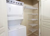 Thumbnail 8 of 17 - Apartments in North Las Vegas NV with In-Unit Washer and Dryer - Sonata - In Unit Laundry Closet With Stacked Washer And Dryer, Multiple Wire Shelving Racks, And Convenient Interior Storage Space