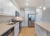 Thumbnail 20 of 46 - a kitchen with white cabinets and a stainless steel refrigerator at Metro Gateway, California