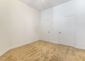 Thumbnail 36 of 46 - a bedroom with white walls and carpet and two doors at Metro Gateway, Riverside, California