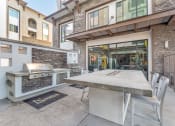 Thumbnail 5 of 46 - a patio with a table and a grill on the side of a building at Metro Gateway, Riverside, CA, 92503