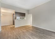 Thumbnail 12 of 22 - an empty living room with wood flooring and a kitchen