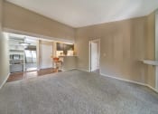 Thumbnail 19 of 29 - an empty living room with carpet and a kitchen
