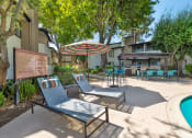 Thumbnail 4 of 29 - Chatsworth Pointe's spacious pool deck with chairs and umbrellas.