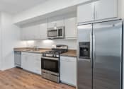 Thumbnail 19 of 46 - a kitchen with white cabinets and stainless steel appliances and a refrigerator at Metro Gateway, Riverside, 92503