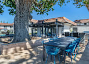 Thumbnail 9 of 28 - a patio with a table and chairs and a large tree at Sage Creek Apartment Homes, Simi Valley, CA