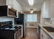 Thumbnail 7 of 19 - a kitchen with white cabinets and black appliances at Scripps Poway Villas, California