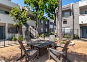 Thumbnail 3 of 19 - a patio with a table and chairs in front of an apartment building at Scripps Poway Villas, Poway California