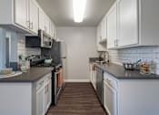 Thumbnail 15 of 28 - a kitchen with white cabinets and gray countertops at Sage Creek Apartment Homes, California, 93063