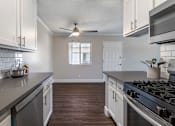 Thumbnail 16 of 28 - a kitchen with white cabinets and gray countertops at Sage Creek Apartment Homes, California