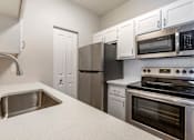 Thumbnail 23 of 32 - Experience culinary bliss in our sleek kitchen adorned with pristine white cabinets and modern stainless steel appliances at Boulders at Lookout Mountain Apartment Homes, Phoenix, AZ