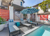 Thumbnail 2 of 28 - Relaxation meets luxury at Independence Plaza: Your oasis awaits, complete with a serene patio, sparkling pool, and inviting lounge chairs under the shade of a vibrant umbrella.
