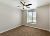 Thumbnail 35 of 42 - Relax in this serene bedroom with a ceiling fan and sunlit window at Trevi Apartment Homes, Chandler, AZ