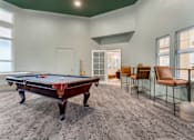 Thumbnail 15 of 33 - A pool table is in the middle of a room with chairs around it.