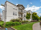 Thumbnail 28 of 33 - A white apartment building with a green lawn in front.